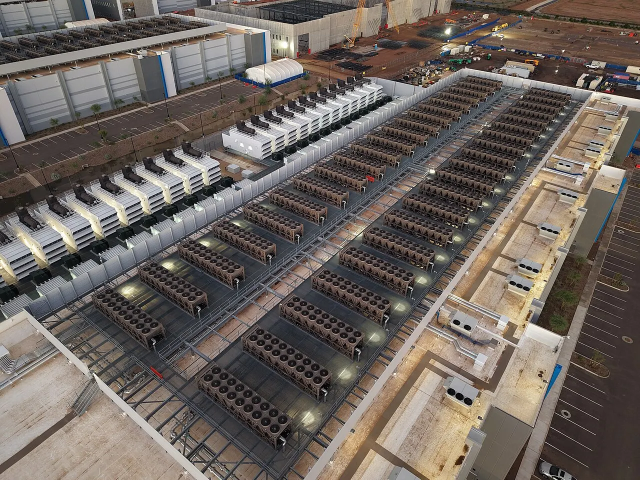 Illustrazione di un enorme datacenter su terreno desertico di fronte a un piccolo quartiere residenziale con cartelli di protesta.